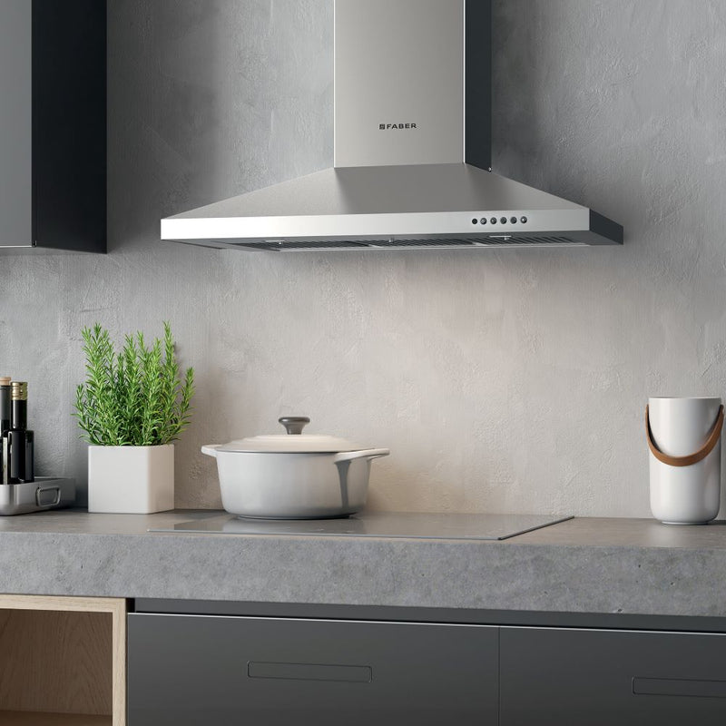 faber dama stainless steel wall kitchen range hood lifestyle image in a minimalist kitchen gray countertops and walls