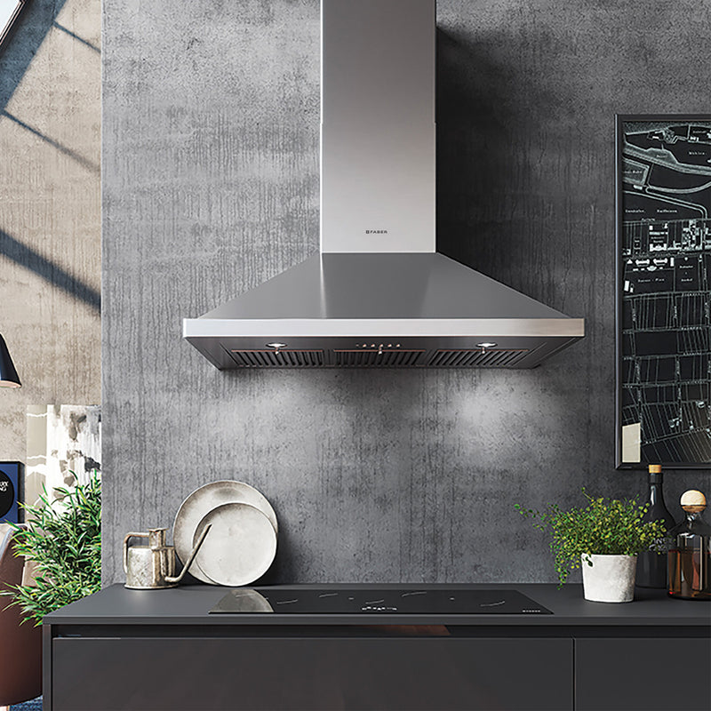 Modern industrial kitchen featuring a Faber Nova Pro stainless steel wall hood over a stop top in grey lower cabinets.