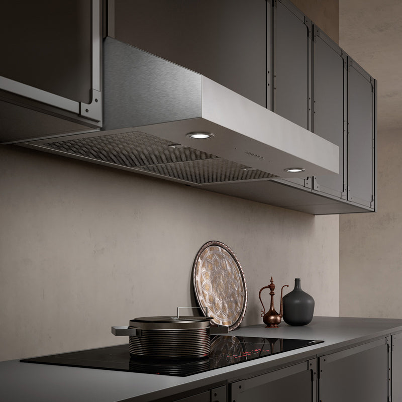 Beige kitchen with grey cabinets featuring a Faber Tivano under cabinet range hood in stainless steel